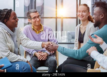 Junge Menschen die Hände schütteln in einem Kreis von Gleichgesinnten Stockfoto