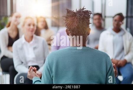 Lächelnder Mann und lächelnde Frau, die sich unterhalten, während sie auf Stühlen sitzen Stockfoto