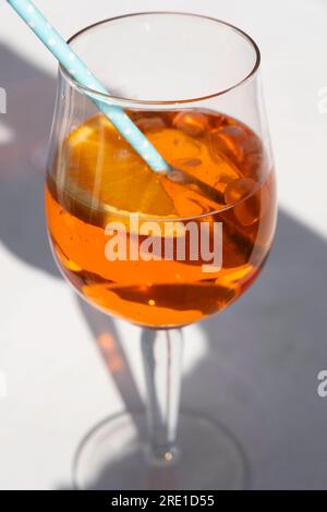 Ein Glas kalter Aperol Spritz mit einem Strohhalm aus Pappe, schräg von oben gesehen mit Schatten. Schmale Schärfentiefe Stockfoto