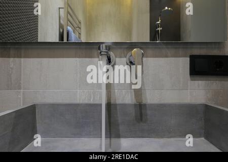 Wasser fließt aus dem Wasserhahn im Badezimmer Stockfoto