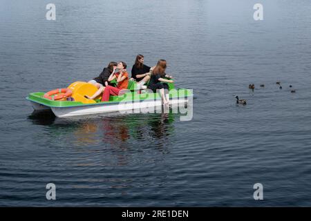 Süße Mädchen haben Spaß in einem Tretboot. Sie füttern die Enten und genießen die Sonne Stockfoto