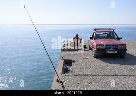 ALBANIEN, Jalë-Strand an der albanischen Riviera in Adria, Mittelmeer, Fischer mit seinem alten deutschen Mercedes-Benz-Auto 190 D, alte Marinebrücke aus der kommunistischen Ära Enver Hoxha / ALBANIEN, Jale Strand der albanischen Riviera an der Adria, Mittelmeer, Angler mit altem Mercedes Benz Auto Stockfoto