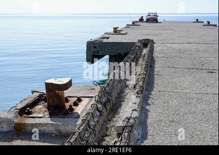 ALBANIEN, Jalë-Strand an der albanischen Riviera in Adria, Mittelmeer, Fischer mit seinem alten deutschen Mercedes-Benz-Auto 190 D, alte Marinebrücke aus der kommunistischen Ära Enver Hoxha / ALBANIEN, Jale Strand der albanischen Riviera an der Adria, Mittelmeer, Angler mit altem Mercedes Benz Auto Stockfoto