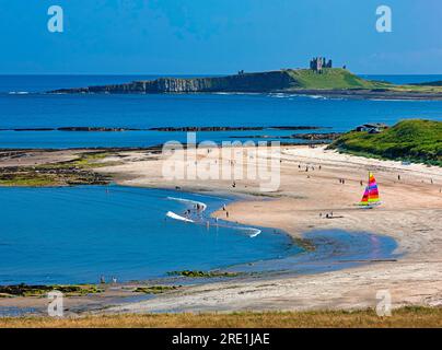 Blick in der Sommersonne in Richtung Dunstanburgh Castle an der Northumberland Coast von Low Newton mit Strand und Strandhütten im Vordergrund Stockfoto