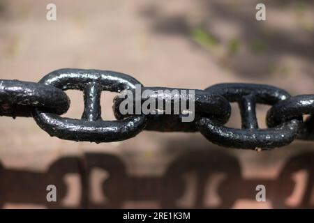 Schwarze Kette. Große Stahlkette. Zaundetails. Kettenglieder. Stockfoto