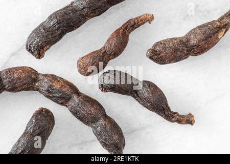 Nahaufnahme von verlängerten afrikanischen schwarzen Paprika-Schoten auf weißem Marmorhintergrund Stockfoto
