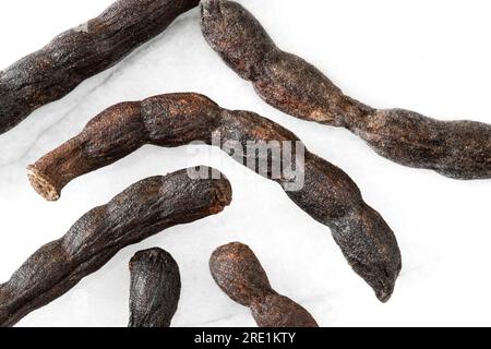 Nahaufnahme von verlängerten afrikanischen schwarzen Paprika-Schoten auf weißem Marmorhintergrund Stockfoto