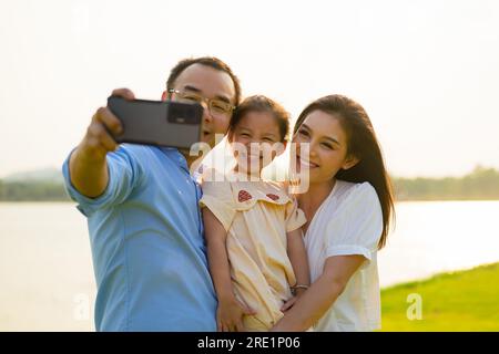 Familie macht Selfie-Fotos mit grüner Wiese und Blick auf den Fluss Stockfoto