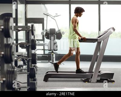 Profilaufnahme eines afroamerikanischen Mannes auf einem Laufband in einem Fitnessstudio Stockfoto