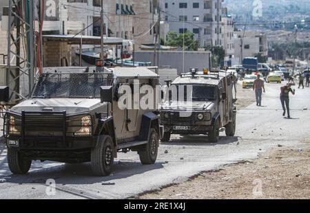 Nalus, Palästina. 24. Juli 2023. Die Palästinenser werfen während einer Militäroperation im Lager östlich von Nablus im besetzten Westjordanland Steine auf die gepanzerten Fahrzeuge des israelischen Militärs. Die israelische Armee hat während einer gemeinsamen Operation zur gleichzeitigen Verhaftung gesuchter Personen die Nour Shams-Lager östlich von Tulkarm und Aqabat Jabr in Jericho, Askar, östlich von Nablus überfallen. Kredit: SOPA Images Limited/Alamy Live News Stockfoto