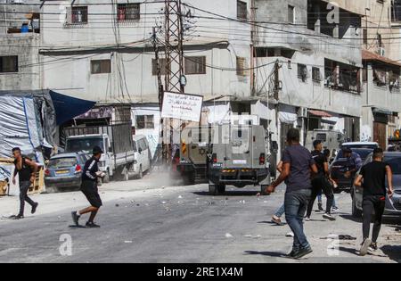 Nalus, Palästina. 24. Juli 2023. Die Palästinenser werfen während einer Militäroperation im Lager östlich von Nablus im besetzten Westjordanland Steine auf die gepanzerten Fahrzeuge des israelischen Militärs. Die israelische Armee hat während einer gemeinsamen Operation zur gleichzeitigen Verhaftung gesuchter Personen die Nour Shams-Lager östlich von Tulkarm und Aqabat Jabr in Jericho, Askar, östlich von Nablus überfallen. Kredit: SOPA Images Limited/Alamy Live News Stockfoto