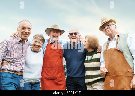 Eine Gruppe lebendiger Senioren in lässiger Outdoor-Kleidung, Arm-in-Arm, lachend und umarmt in einer Outdoor-Umgebung. Stockfoto