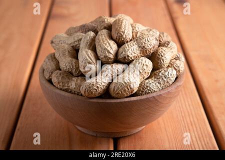 Schüssel voll mit geschälten Erdnüssen auf einem Holztisch Stockfoto