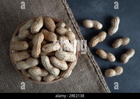 Schale voll mit geschälten Erdnüssen auf dunklem Hintergrund Stockfoto