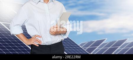 Weibliche Ingenieurin, die im Hintergrund auf Solaranlagen steht Stockfoto