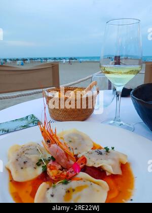 Nahaufnahme von gegrillten Garnelen auf einem Teller mit einem Glas Wein auf Oliven. Stockfoto