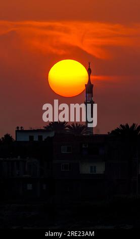 Die Sonne geht hinter dem Minarett auf dem Nil unter Stockfoto