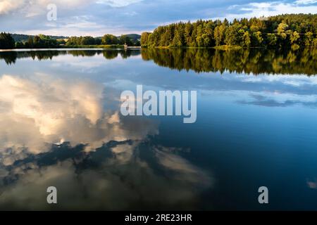 Ein bayerischer See (Postfeldener Stausee) im Naturschutzgebiet Höllbachtal zur goldenen Stunde, wobei der Himmel im See reflektiert. Deutschland. Stockfoto