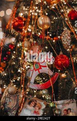 Klassische Weihnachtsspielzeugfigur eines lustigen Pferdes, das an den Weihnachtsbaumzweigen hängt. Festliche magische Details zum Neujahr Stockfoto