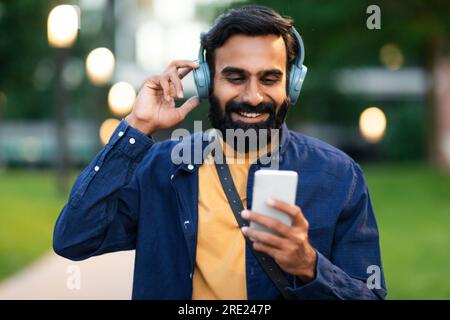 Ein Araber mit Kopfhörern, der draußen Videoanrufe mit dem Smartphone macht Stockfoto