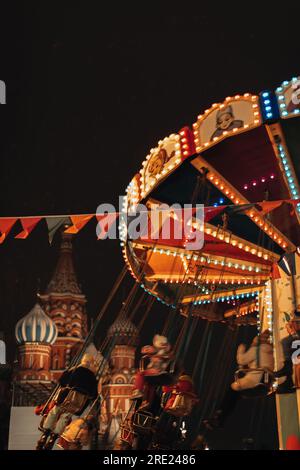 Goldene Magie Retro-Kinderkarussell-Girlande-Bokeh leuchtet vor dem festlichen Moskau. Vertikale Postkarte für Winterferien Stockfoto