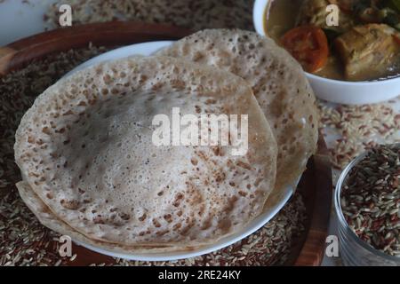 Rajamudi-Reis-Appam serviert mit kerala-Hühnchen-Curry. Reiscrepes oder Pfannkuchen mit fermentiertem Ramamudi-Reisteig und Kokosmilch. Eine Version von Stockfoto