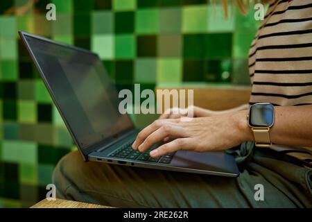 Die Hände tippen auf der Laptop-Tastatur. Nahaufnahme einer Frau, die im Café ein Notebook benutzt Stockfoto