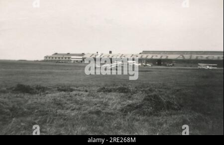 Brough, East Yorkshire. c.1938 – Eine Fotografie der Flugzeugfabrik Blackburn am Brough Aerodrome, die sich im East Riding of Yorkshire, England, befindet. Vor dem Gebäude parken mehrere Flugzeuge, darunter das britische Flugzeug Swallow 2 Monoplane, G-AFIK. Dieses Flugzeug war ursprünglich Eigentum von Blackburn Aircraft Limited. Stockfoto