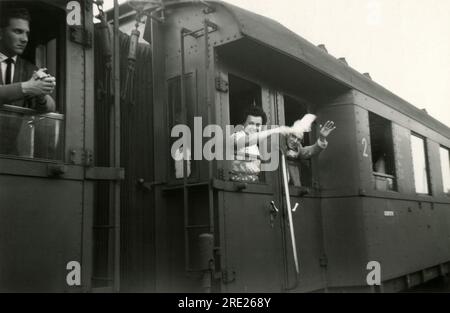 Deutschland. 1950er – Eine Frau und ein Mann winken einem Eisenbahnwagen zum Abschied zu. Die Dame winkt mit einem weißen Taschentuch. Stockfoto