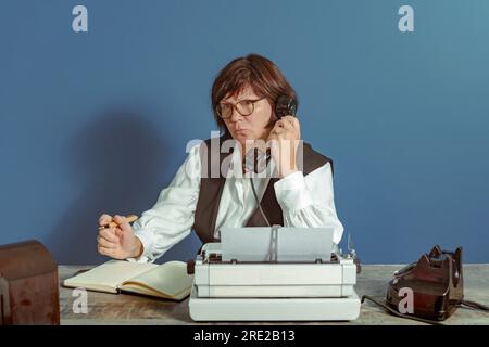 Brünette Sekretärin aus der Vergangenheit bei der Arbeit. Vintage-Konzept. Tisch mit Telefon und Schreibmaschine. Stockfoto