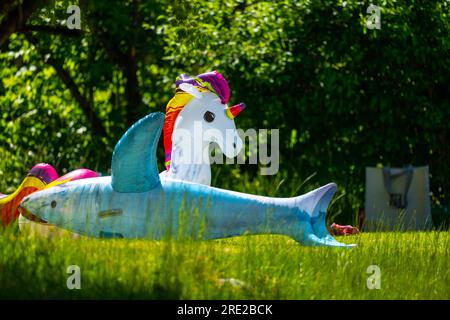 Aufblasbare Flöße in Form eines Einhorns und ein Hai auf Gras Stockfoto