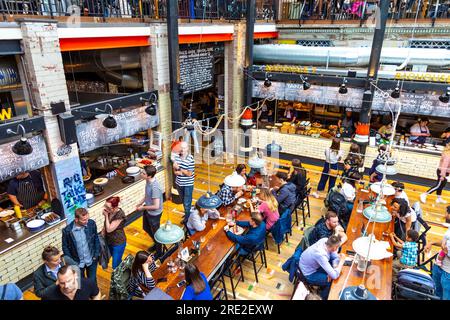 Die Menschen essen in einem Food Court, Interieur des Mackie Bürgermeister in einem ehemaligen Fleischmarkt Gebäude in Manchester, Großbritannien Stockfoto