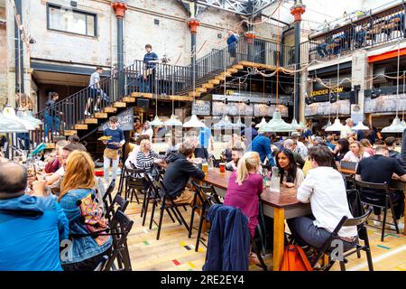 Die Menschen essen in einem Food Court, Interieur des Mackie Bürgermeister in einem ehemaligen Fleischmarkt Gebäude in Manchester, Großbritannien Stockfoto