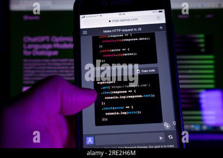 Azoren, Portugal - 16.01.2023: Smartphone mit AI Chat GPT sofortige Reaktion der Codeprogrammierung. Im Hintergrund ein Laptop-Bildschirm mit ChatGPT-Webseite. Stockfoto