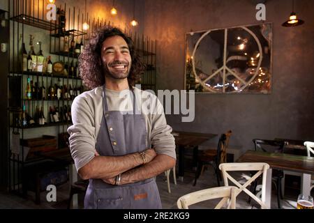 Porträt eines jungen Kaukasiers, der in einem Restaurant in die Kamera schaut. Stolzer und lächelnder Kellner Stockfoto