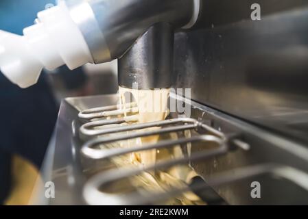 Nahaufnahme der Pasteurmaschine, die Eiscreme in einen Gefrierschrank aus Stahl gießt. Konzept der Eiscremeherstellung. Hochwertiges Foto Stockfoto