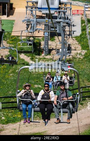 Kasachstan, Skigebiet Shymbulak. Touristen fahren im Sessellift. Stockfoto