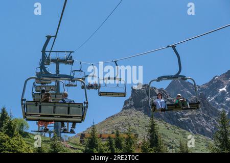 Kasachstan, Skigebiet Shymbulak. Touristen fahren im Sessellift. Stockfoto