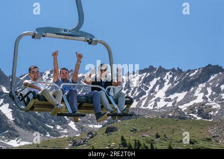 Kasachstan, Skigebiet Shymbulak. Touristen fahren im Sessellift. Stockfoto