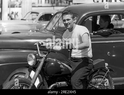 San Francisco, Kalifornien: ca. 1955 Ein junger Mann auf einem Motorrad neben seinem Kumpel, der eine Lederjacke im Auto trägt Stockfoto