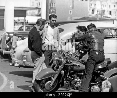 San Francisco, Kalifornien: ca. 1955 vier Teenager, zwei auf Motorrädern, plaudern auf einem Parkplatz. Stockfoto