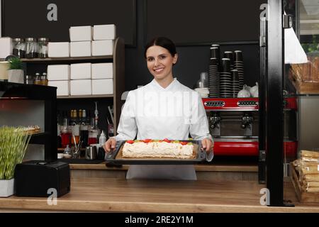 Happy Baker präsentiert köstlichen Kuchen mit Erdbeeren im Café Stockfoto