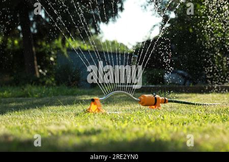 Automatischer Sprinkler zur Bewässerung von Grüngras auf dem Rasen im Garten. Bewässerungssystem Stockfoto