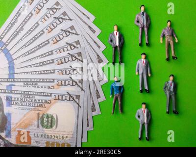 Miniaturleute und Banknoten, Geschäftsmann auf grünem Hintergrund. Geschäftskonzept. Stockfoto