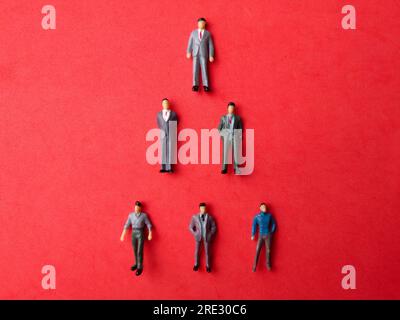 Miniaturleute, Geschäftsmann auf rotem Hintergrund. Das Busenkonzept Stockfoto