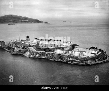 San Francisco, Kalifornien: 1946. Blick aus der Vogelperspektive auf Alcatraz Island und Gefängnis in der Bucht von San Francisco. Angel Island ist dahinter mit einem „Welcome Home, Well done“-Schild auf der Seite für die Truppen, die nach dem Ende des Zweiten Weltkriegs vom Asia-Pacific Theater nach Hause zurückkehren. Stockfoto