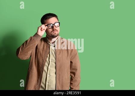 Ein gutaussehender Mann mit stilvoller Brille auf grünem Hintergrund Stockfoto
