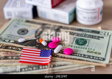 Medizinische Kosten, großes Pharmakonzept mit einem Glas Wasser, verschiedene Medikamente, US-Dollar-Scheine und die amerikanische Flagge. Stockfoto