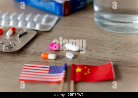 Ein pharmazeutischer, medizinischer Wettbewerb, Konflikt, Konzept mit den amerikanischen und chinesischen Flaggen und verschiedene Medikamente auf einem Schreibtisch. Stockfoto