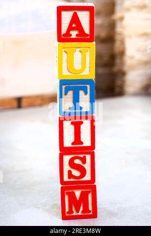 Autismus wird in Bausteinen für Kinder auf meliertem Grau geschrieben. Stockfoto